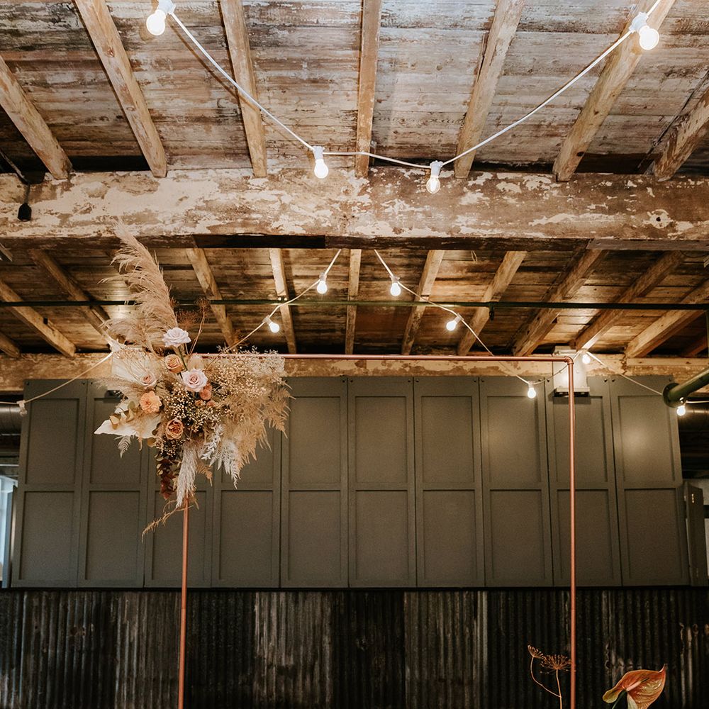 Copper archway with dried and fresh flower autumnal toned displays for industrial wedding with candles 