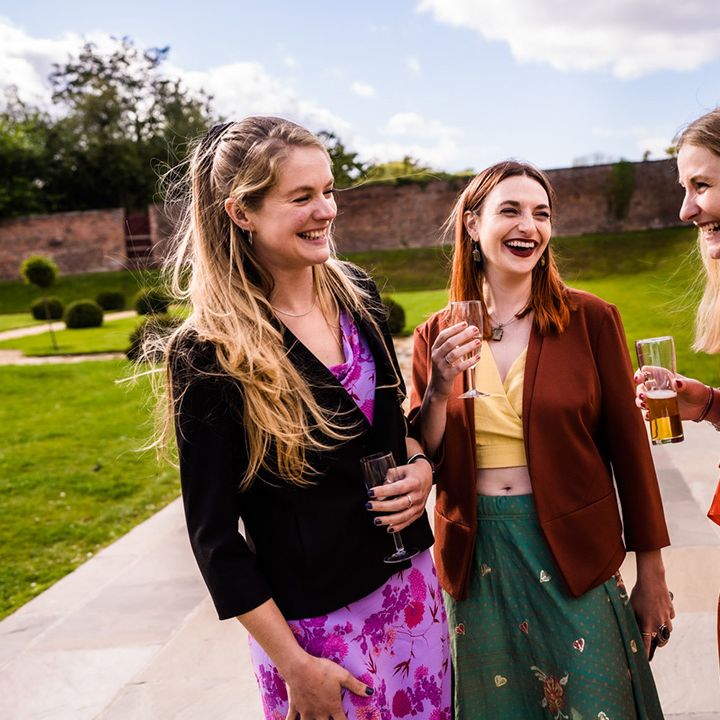 Wedding guests socialise together outside ceremony room 