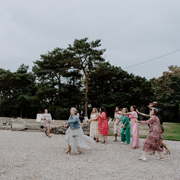 The bride tosses her bouquet for the single female wedding guests hoping to get married 