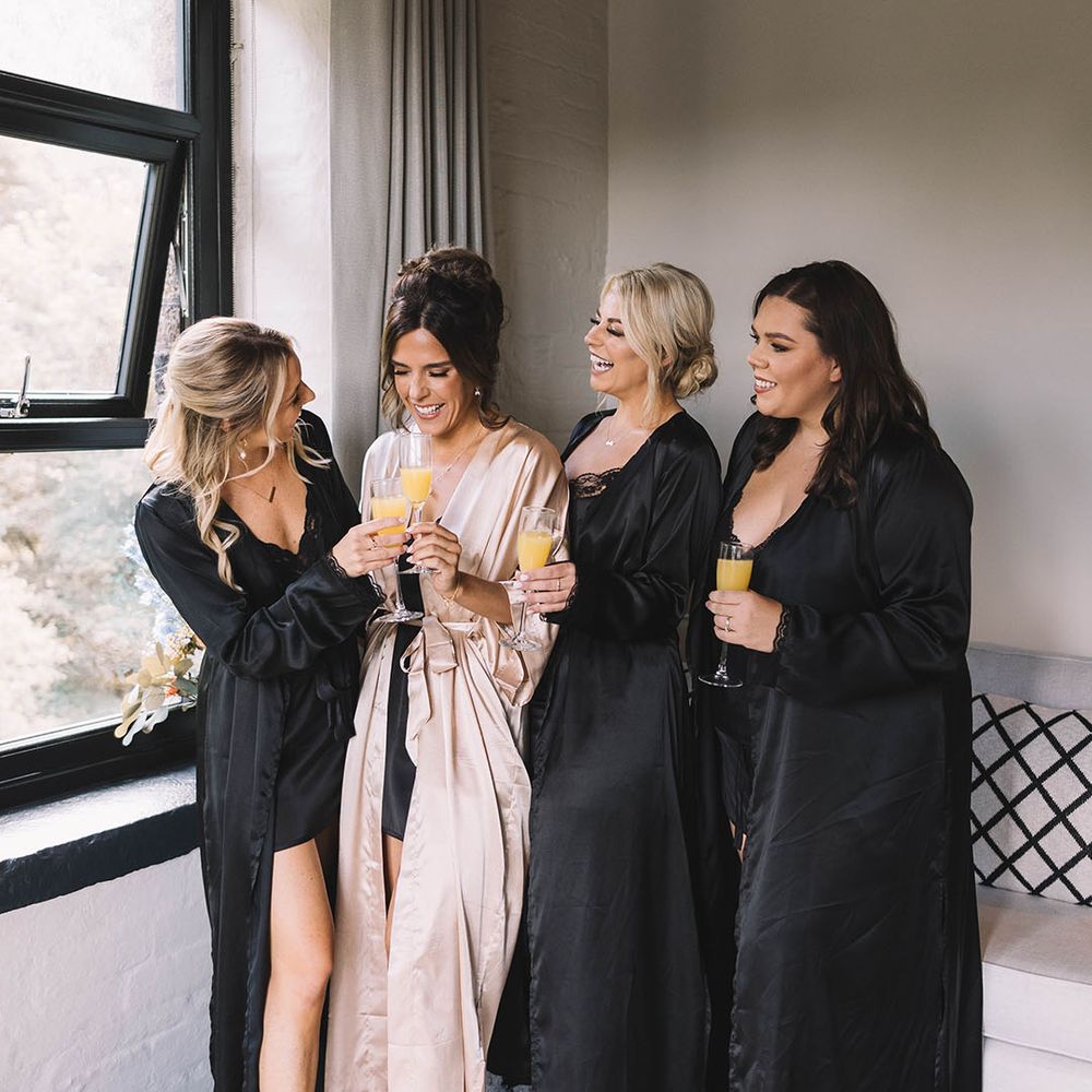 The bridesmaids wearing black satin robes 