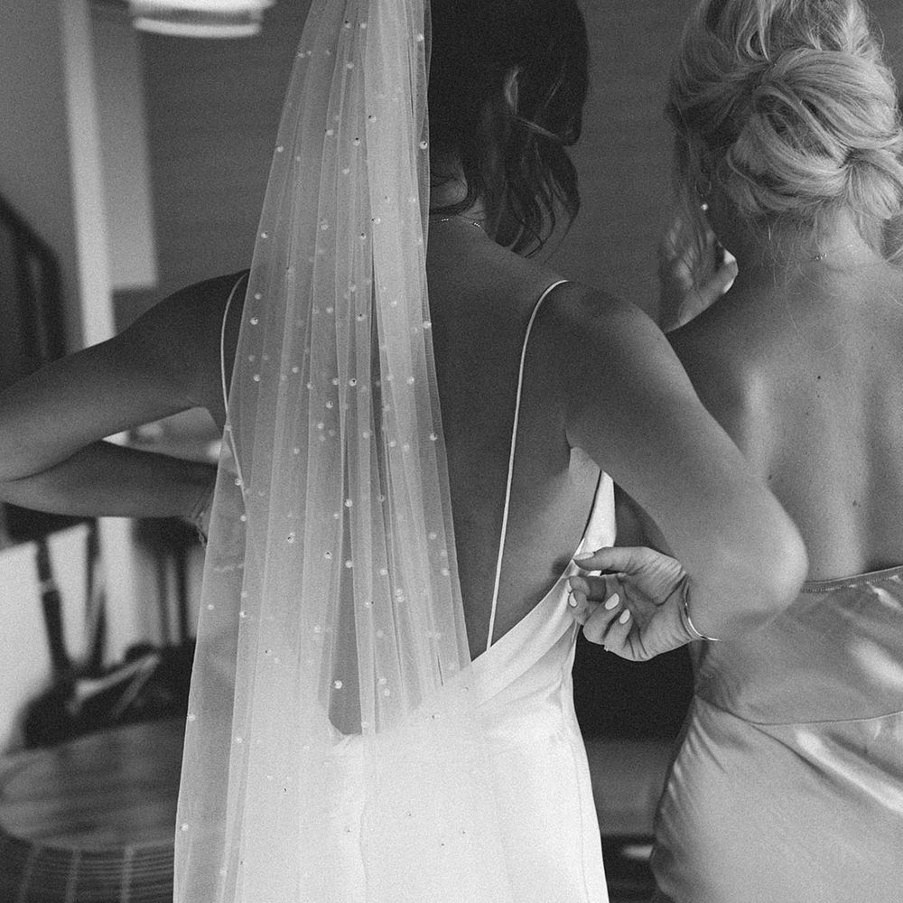 Bride wearing a pearl wedding veil paired with her satin slip wedding dress 