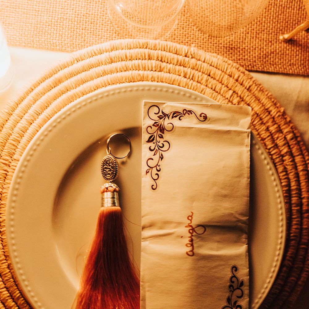 Wicker place mat and white plate with decorated napkin and place name 