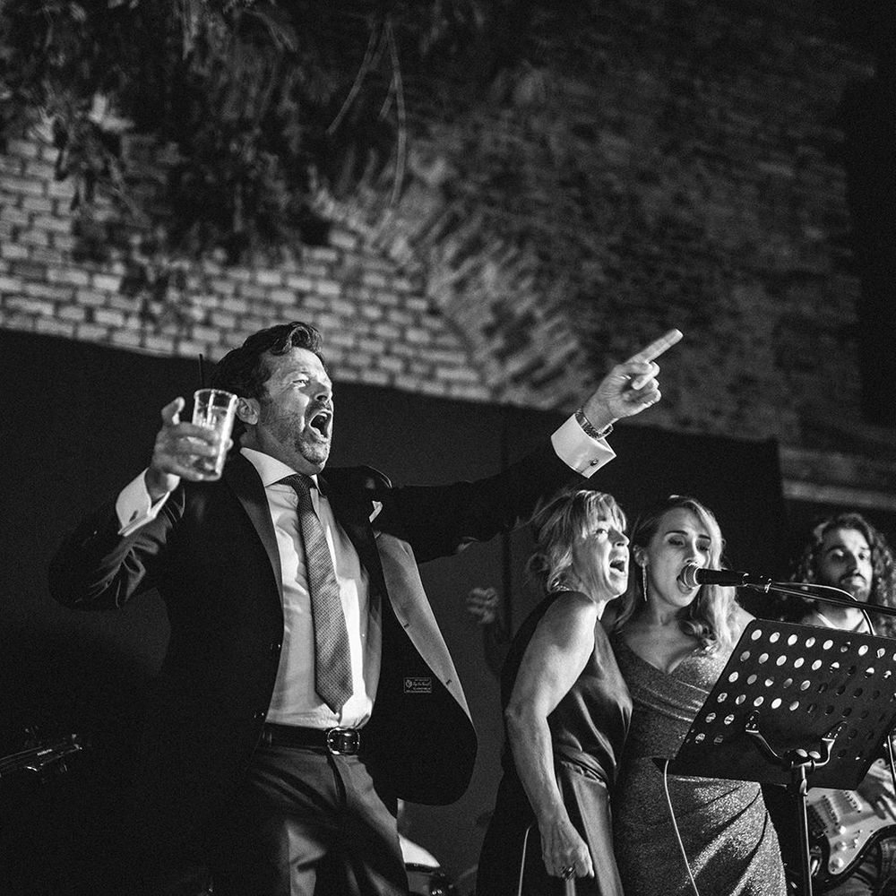 Father of the bride singing with the wedding entertainment at Italian beach wedding reception 