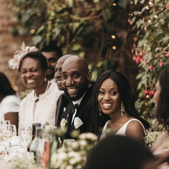 Bride and groom smiling sitting at the top table during the wedding speeches 