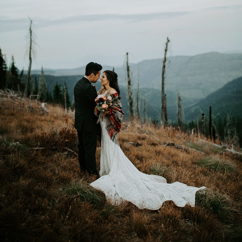 Bride & groom embrace one another on mountain top 