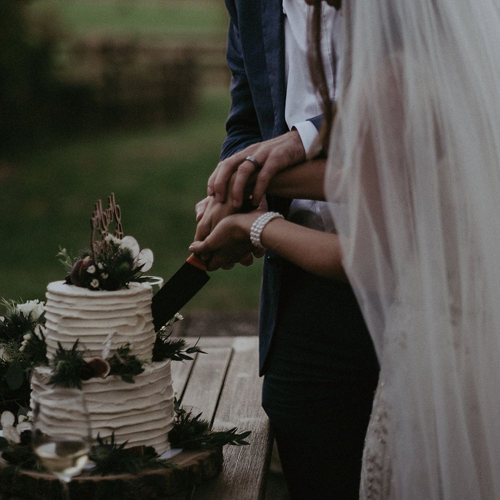 Bride & groom cut cake on their wedding day outdoors