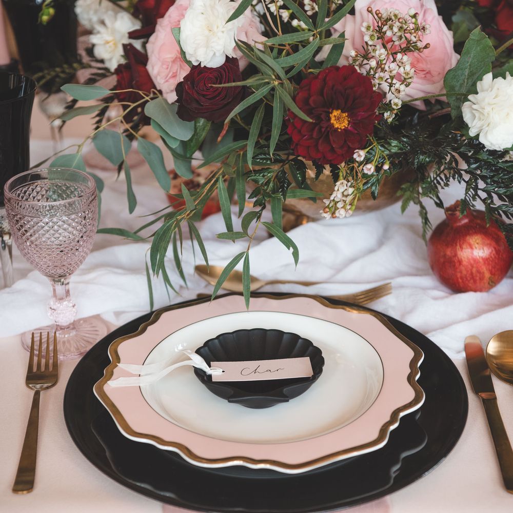 Wedding table decor with black charger plate, pink and gold tableware and floral centrepiece 