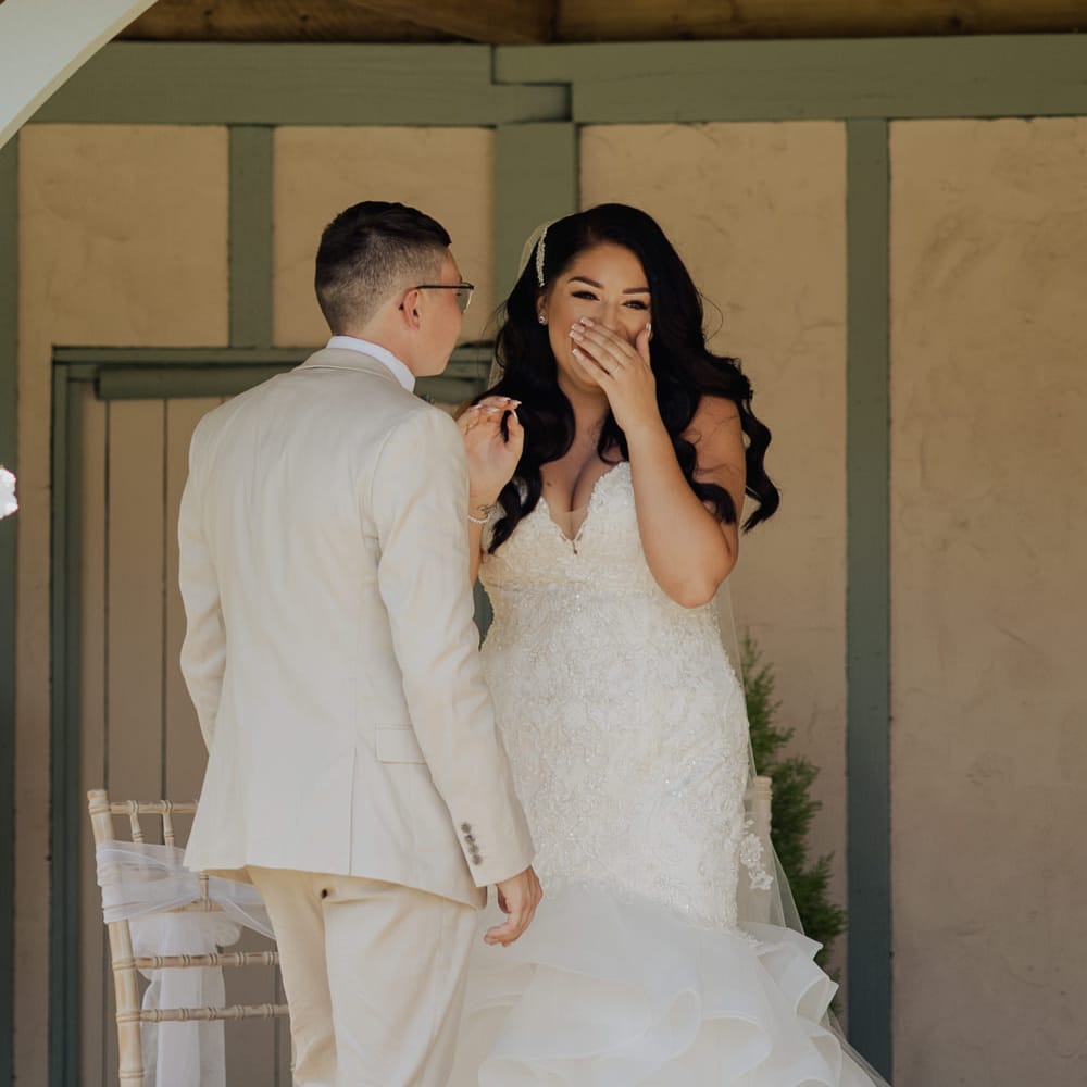 Bride in a strapless fishtail wedding dress laughing during the outdoor wedding ceremony at Cooling Castle Barn 