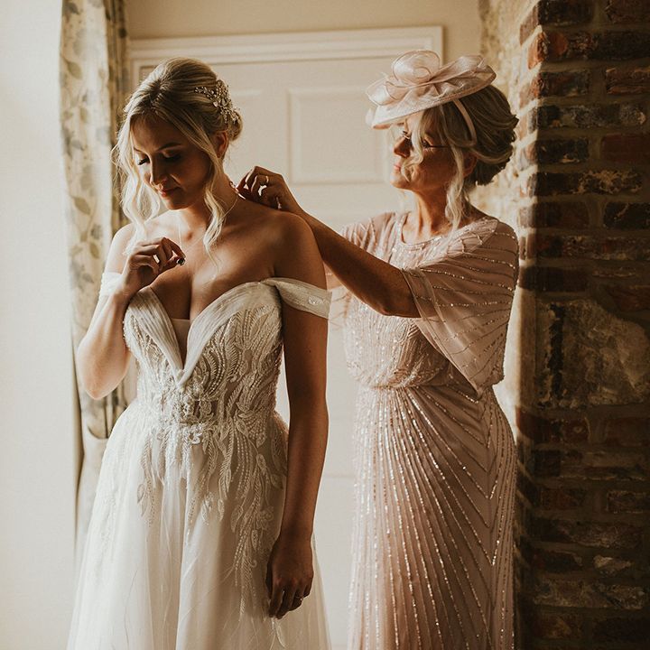 Bride puts on Pronovias lace wedding dress with off the shoulder detail