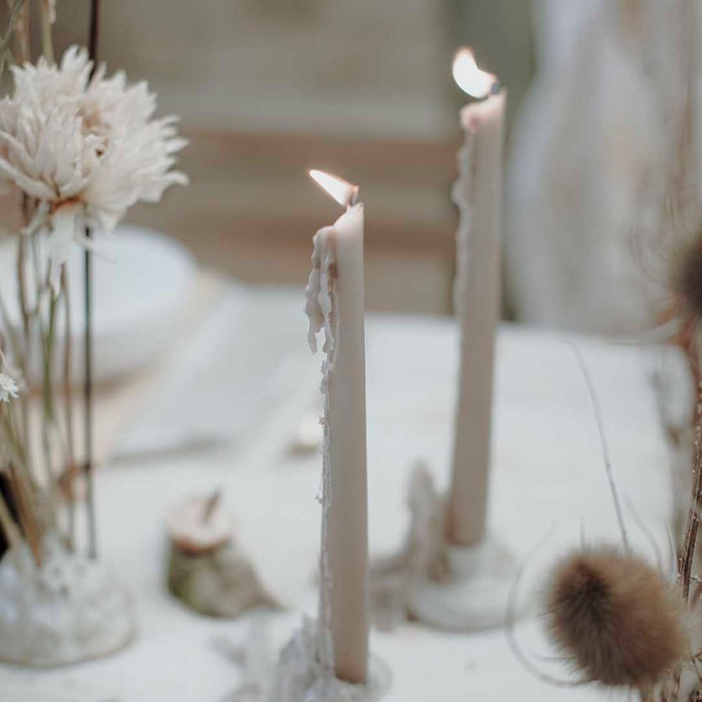 taupe taper candle with wax running down the side 