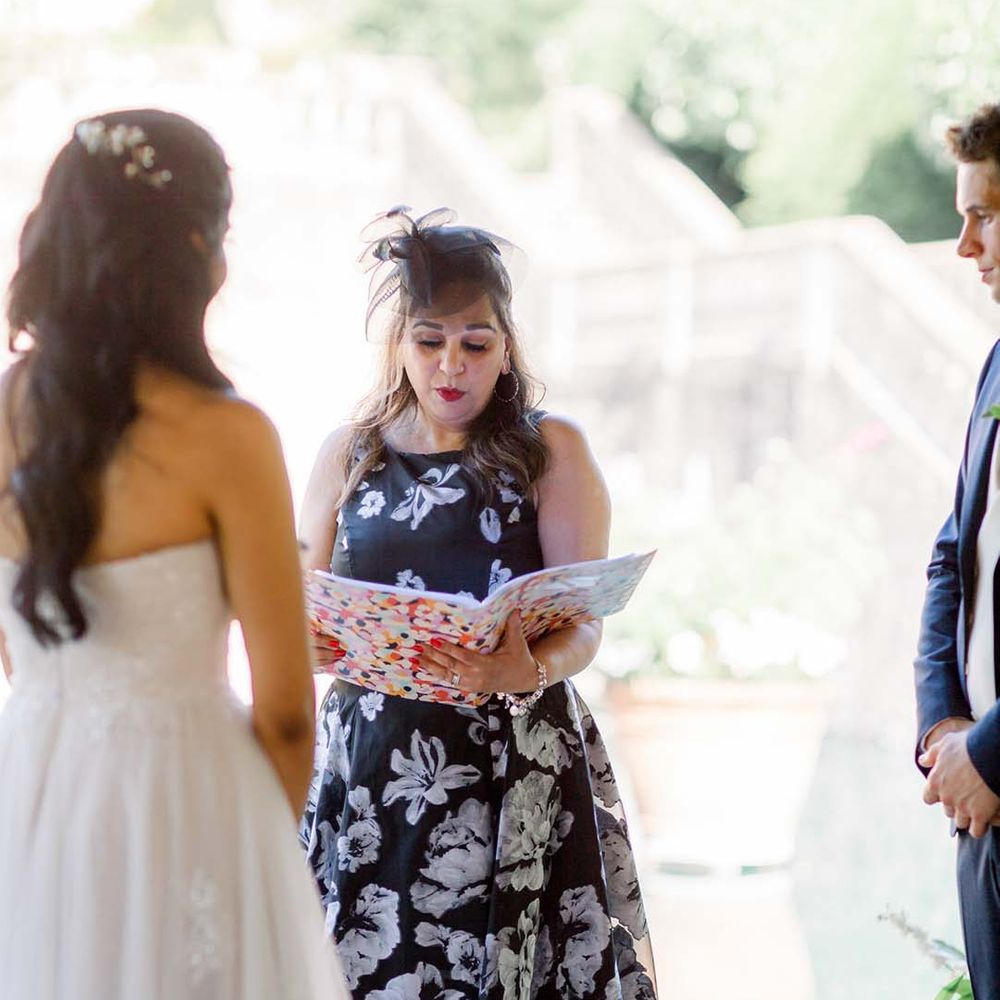 Celebrant during ceremony as bride & groom stand beside one another on their wedding day