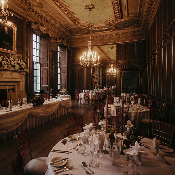 Gosfield Hall wedding reception complete with red ribbon tied around chairs and white tablecloths 