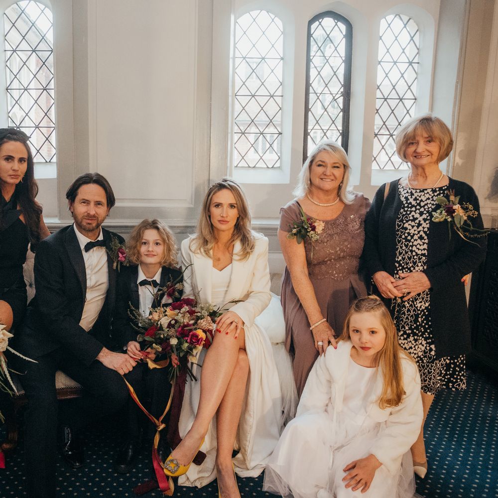 Bride & groom sit with their son and wedding guests at Gosfield Hall on their wedding day