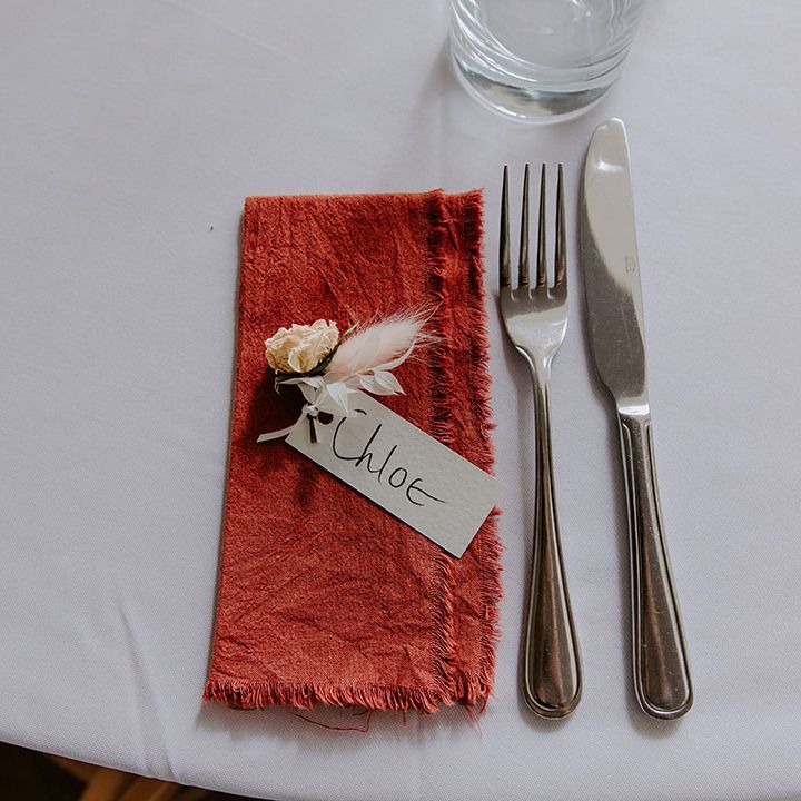 Fabric napkin with frayed edges complete with small floral decor and place name