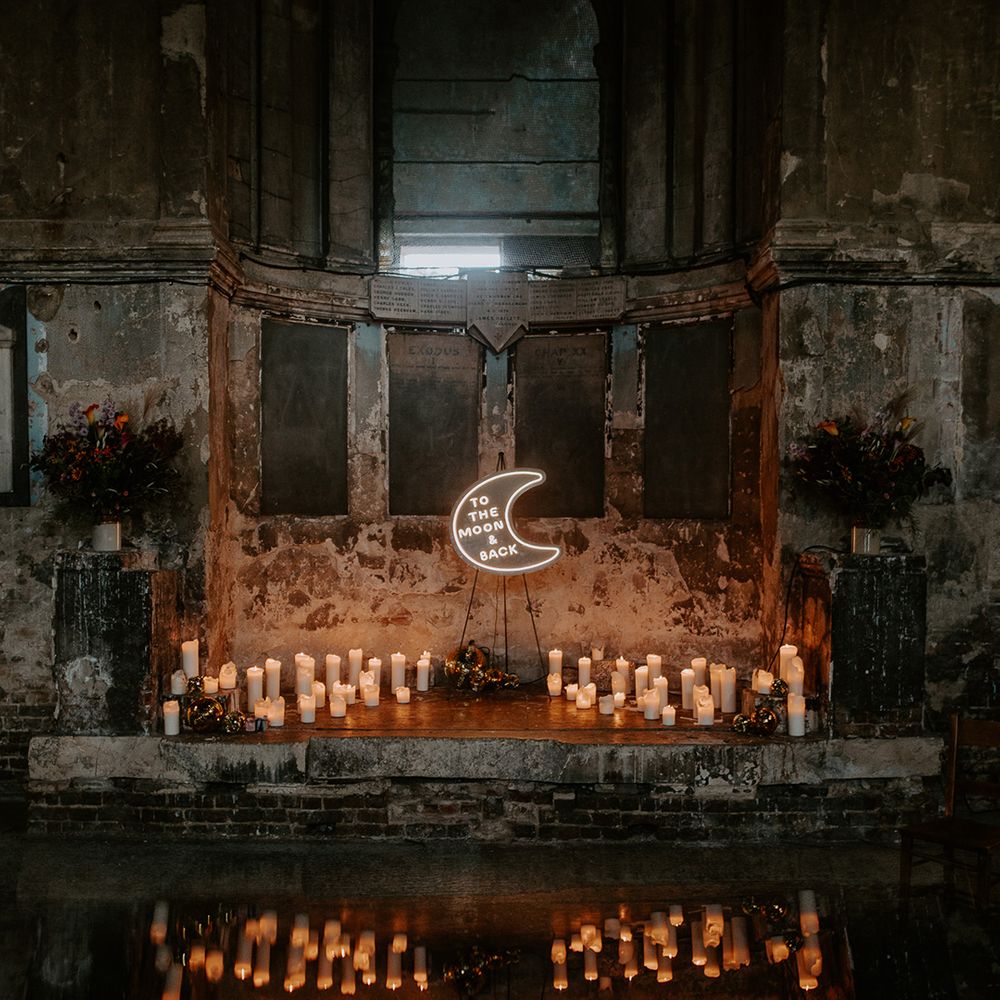 Stunning wedding alter consisting of candles and a moon neon sign at unique wedding venue in London