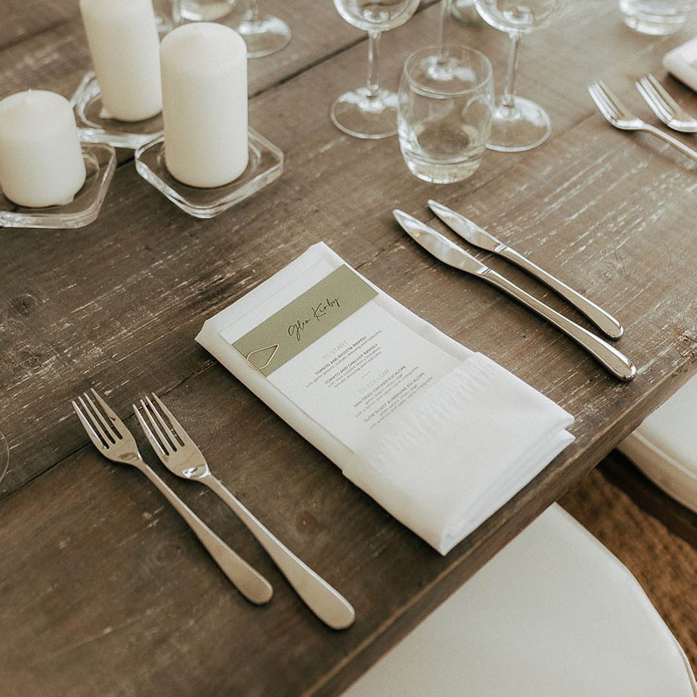Classic white stationery on wooden banquet table for marquee reception