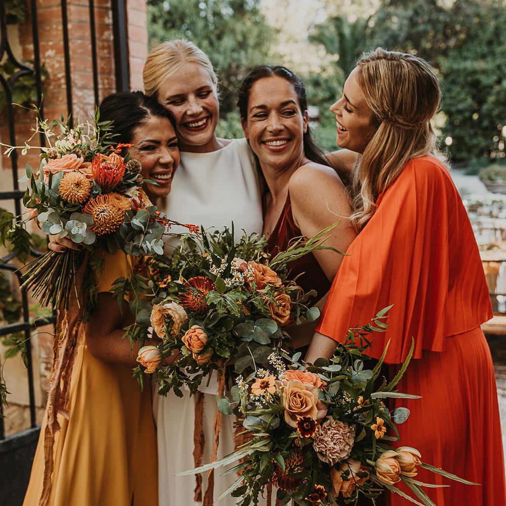 Bridal party in earthy toned dresses hugging 