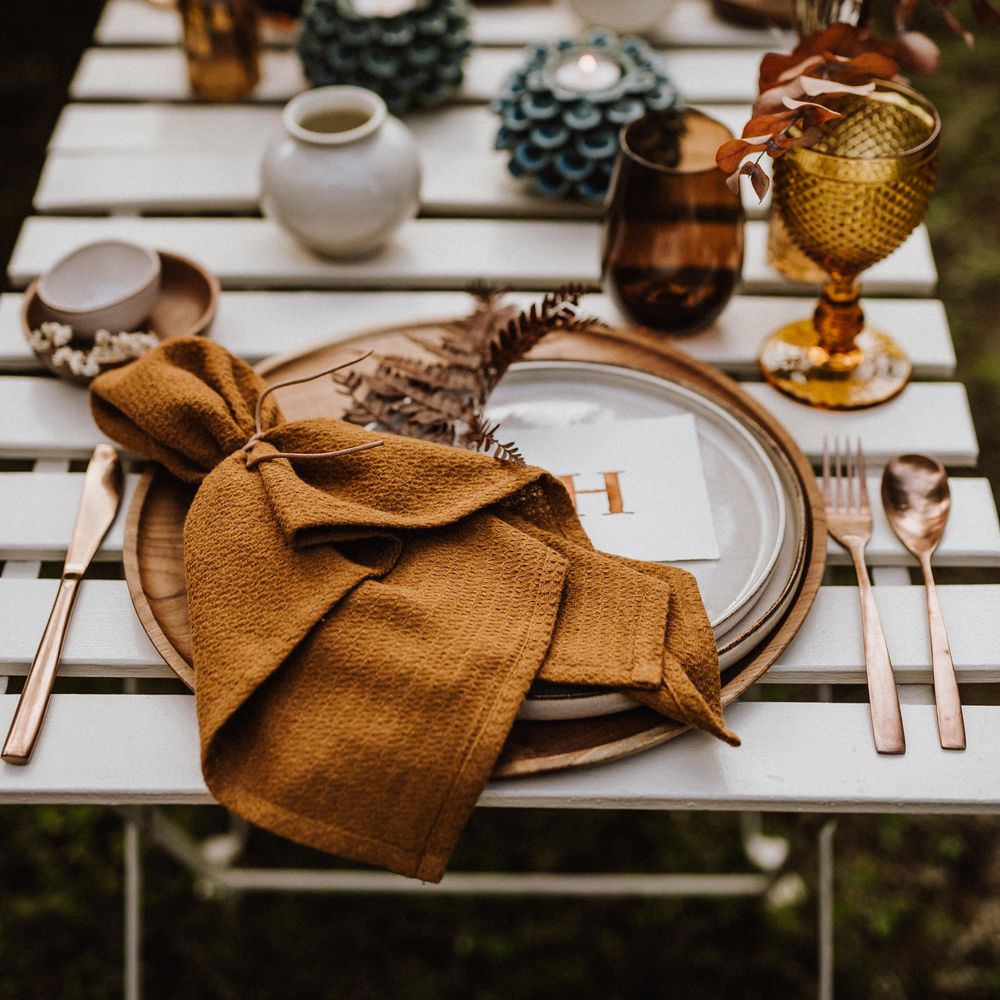Boho table setting with brass knives and forks and wooden placemats