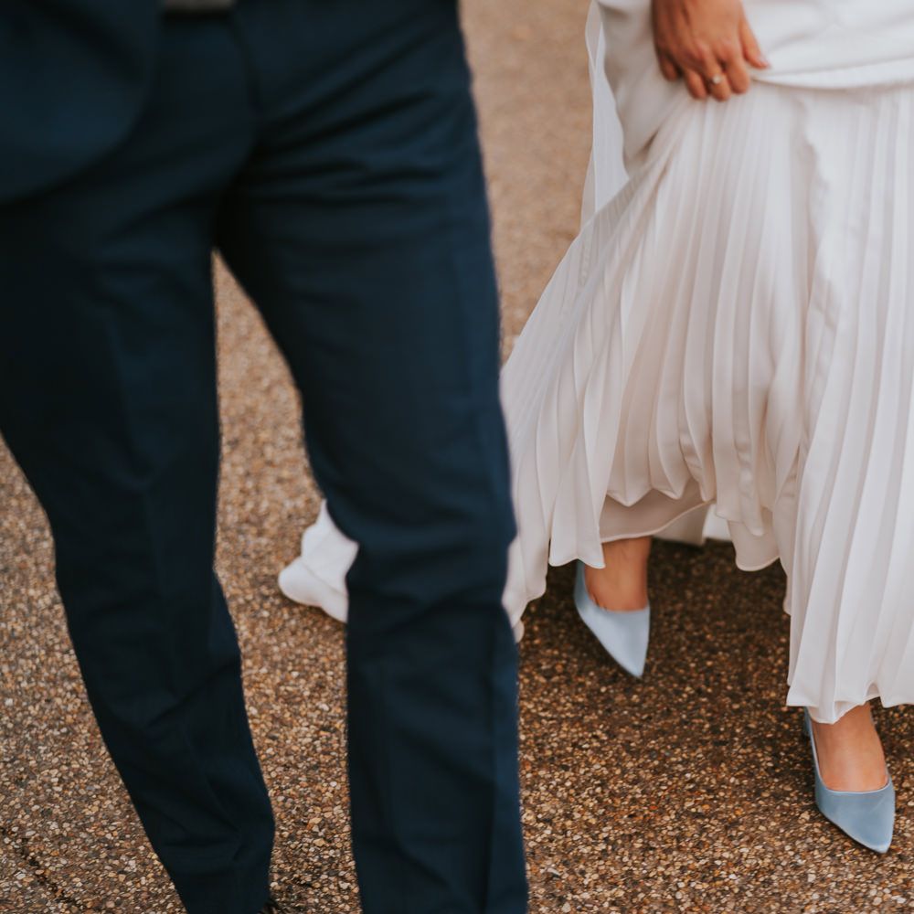 Bride & groom walk together outdoors with bride wearing Rainbow Club shoes