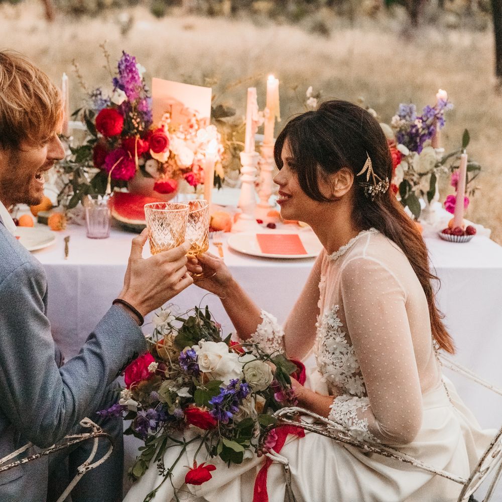 Bride & groom cheers sat at table with bright decoration 