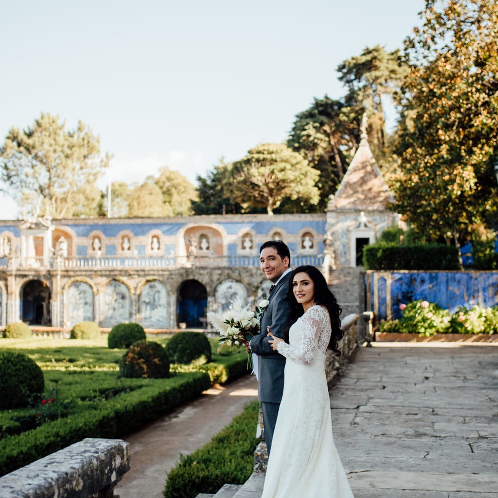 Bride & groom look toward camera as they smile on their wedding day whilst outdoors in Lisbon