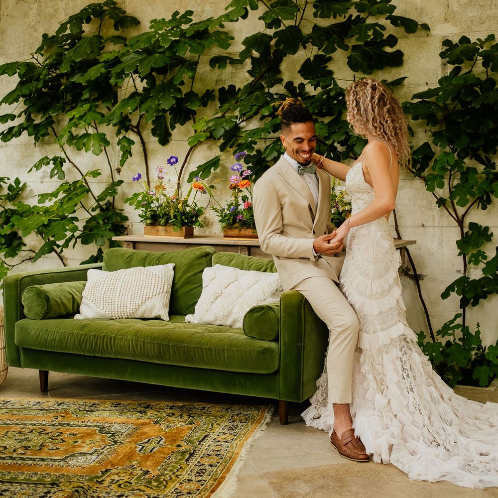 Groom in a beige suit and green bow tie and bride in a boho lace dress at their colourful fiesta theme wedding 