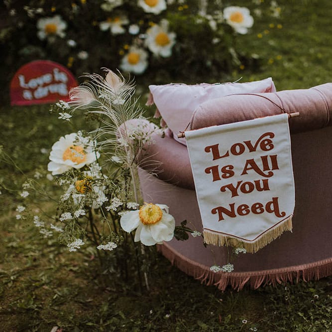 Love Is All You Need fabric banner wedding sign resting on the back of a retro sofa 