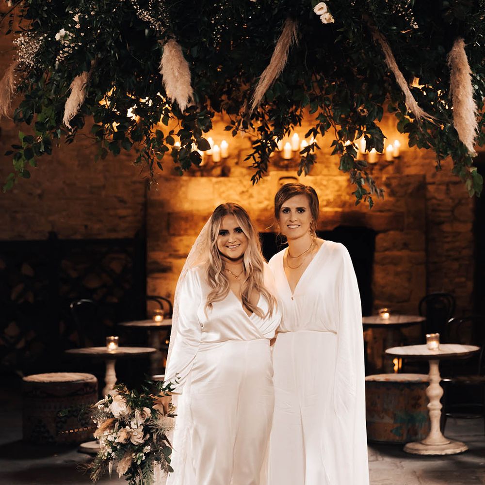 Brides stand with one another in rustic venue for post wedding couples portraits