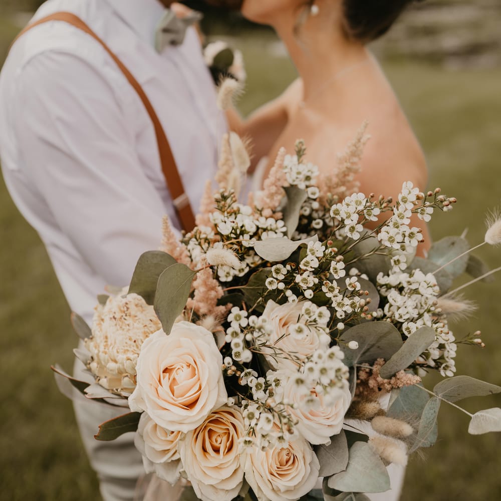 Bride & groom kiss on their wedding day as bride holds out her floral bouquet | Mark Bamforth Photography
