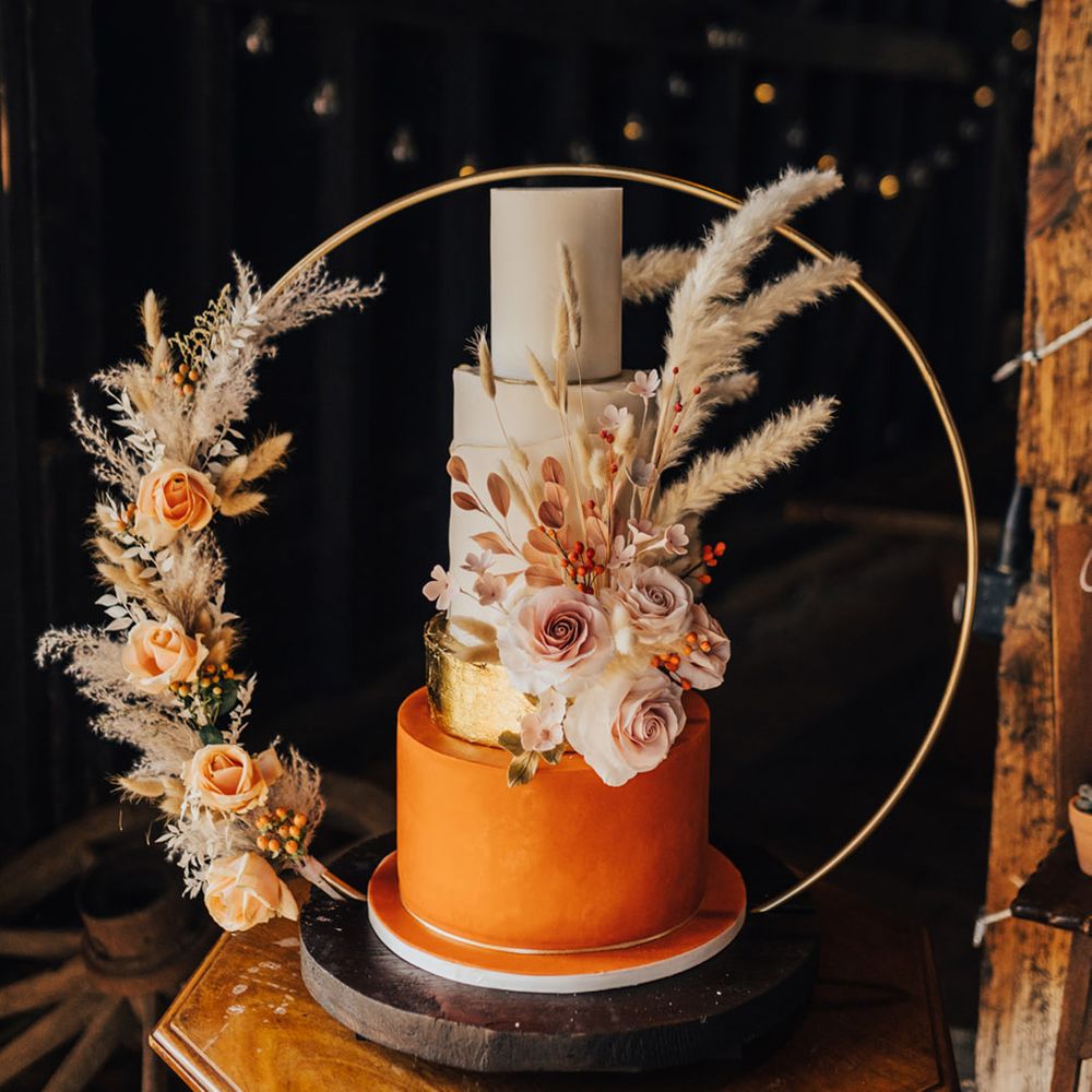 3 Tier layer cake with accent colour bright orange icing in between pampas grass decoration