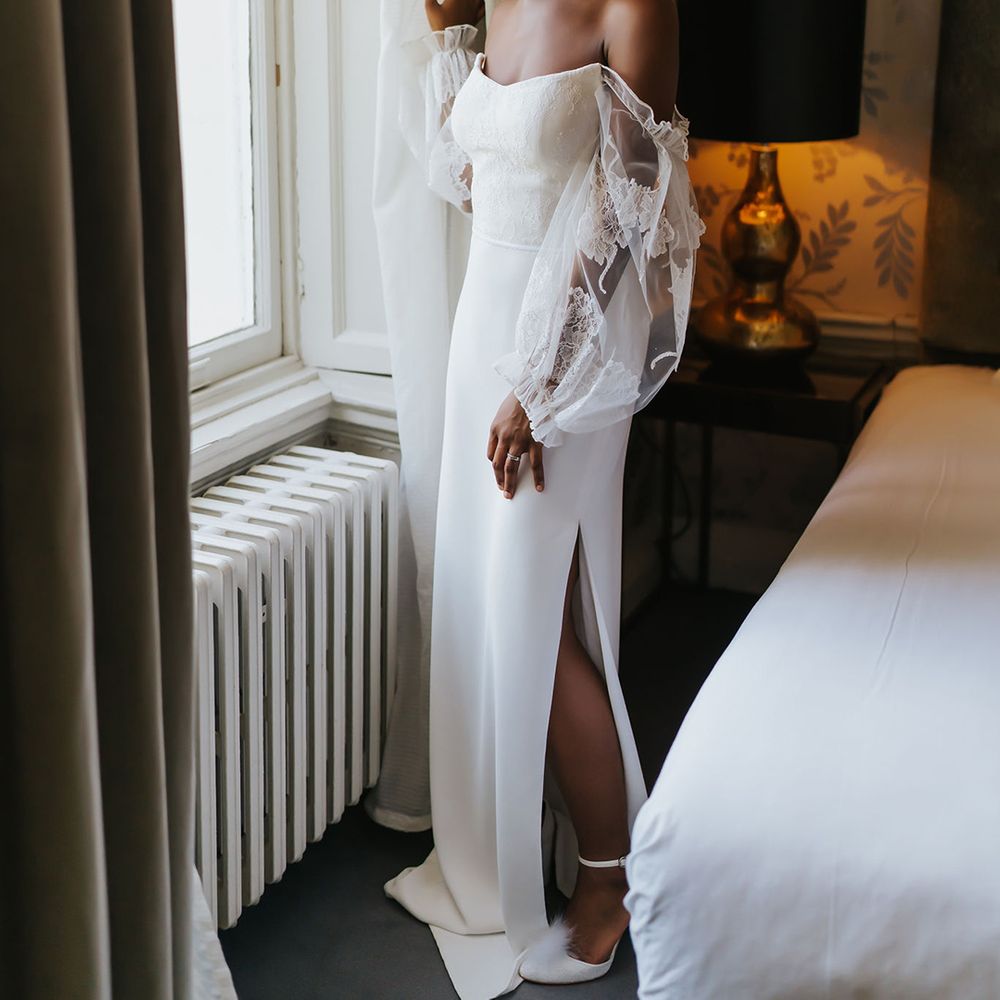 Black bride with short afro hair in a strapless wedding dress with detachable lace sleeves and side slit on the wedding morning 