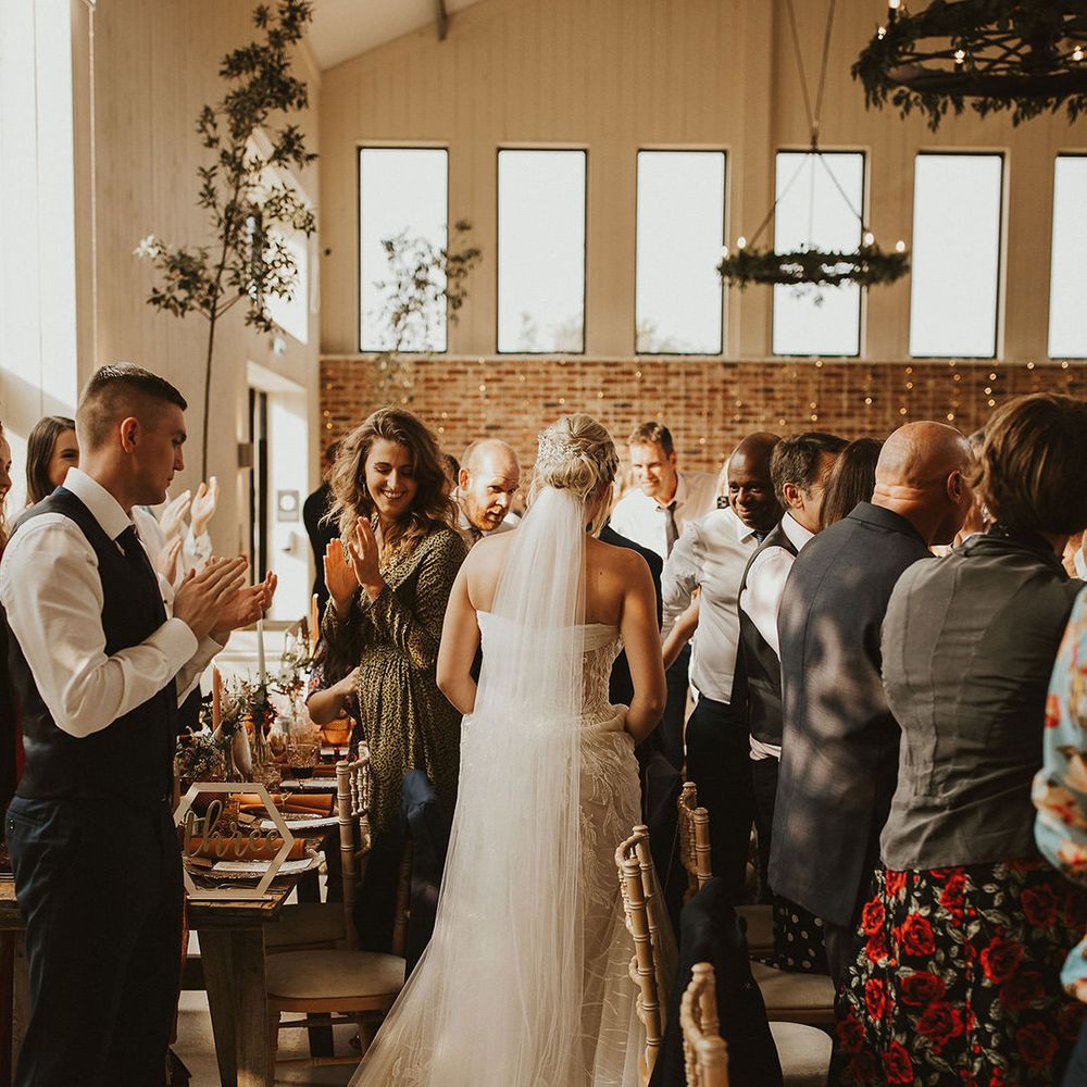 Bride with veil makes entrance into wedding breakfast