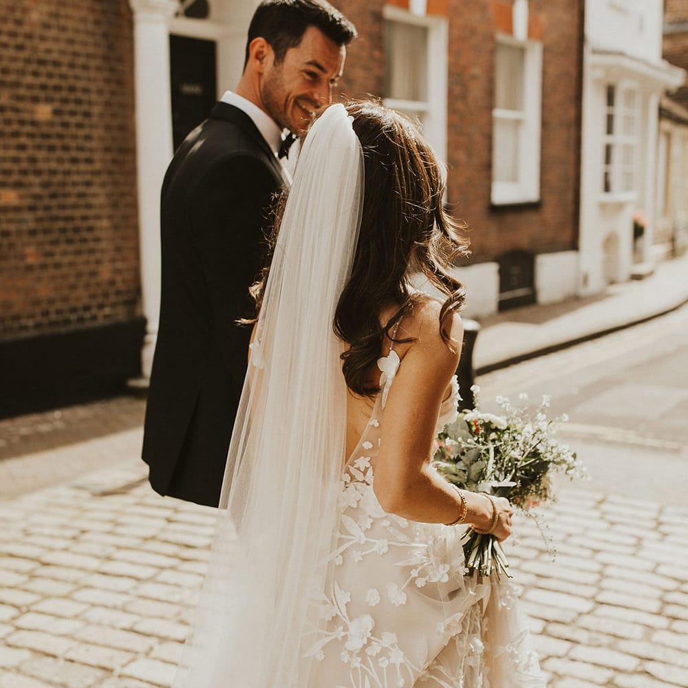Bride & groom walk down city street together on their wedding day