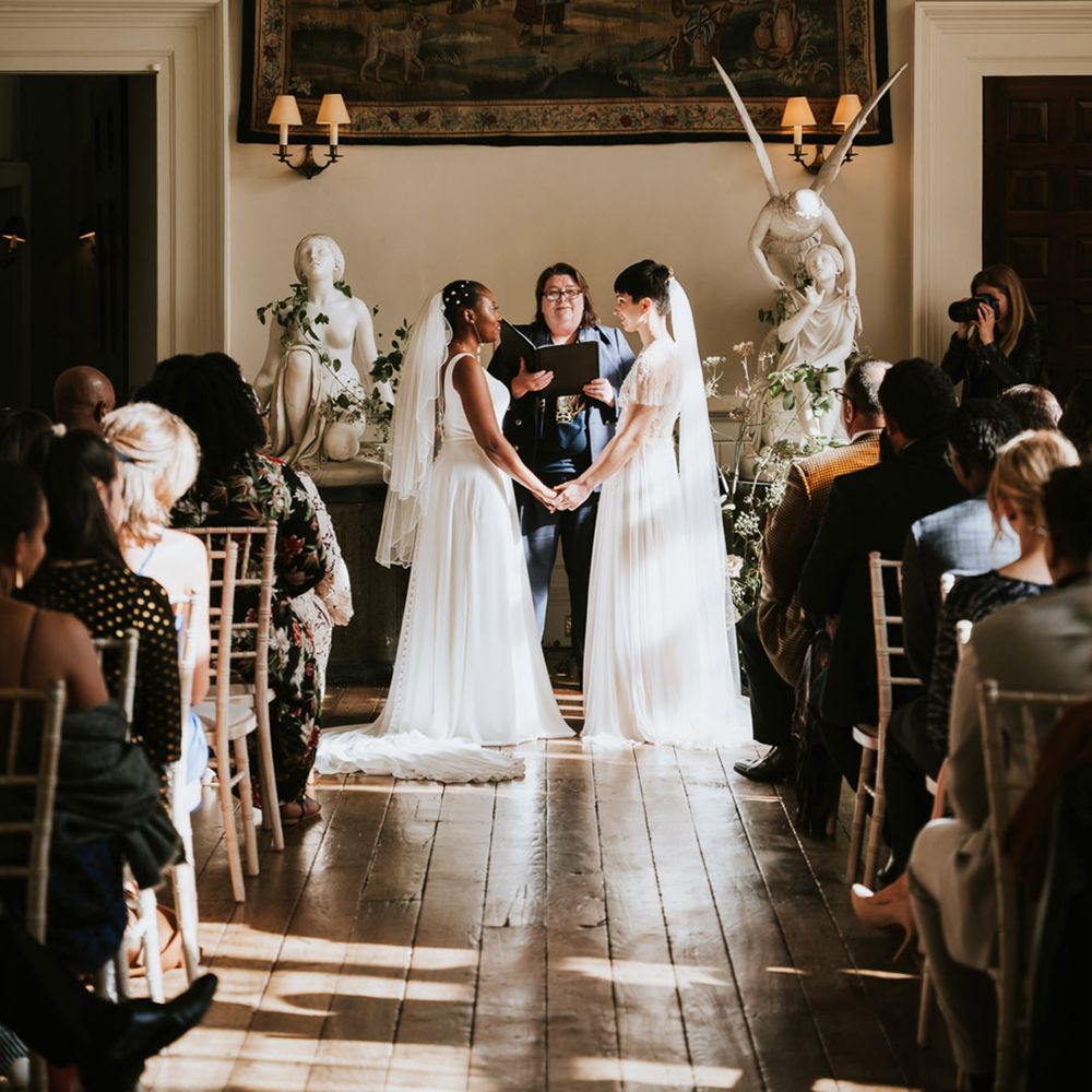 Same sex civil wedding ceremony at Elmore Court with two brides holding hands exchanging vows 