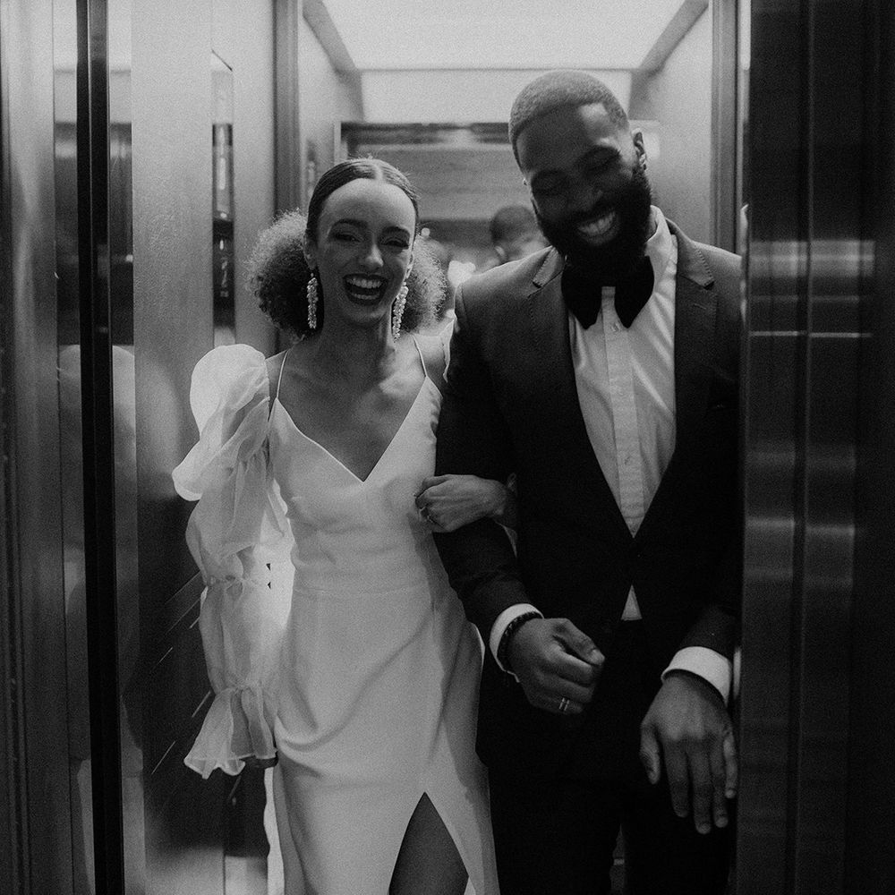 Black bride and groom in black tie attire exiting the lift at Mayfair Townhouse wedding venue 
