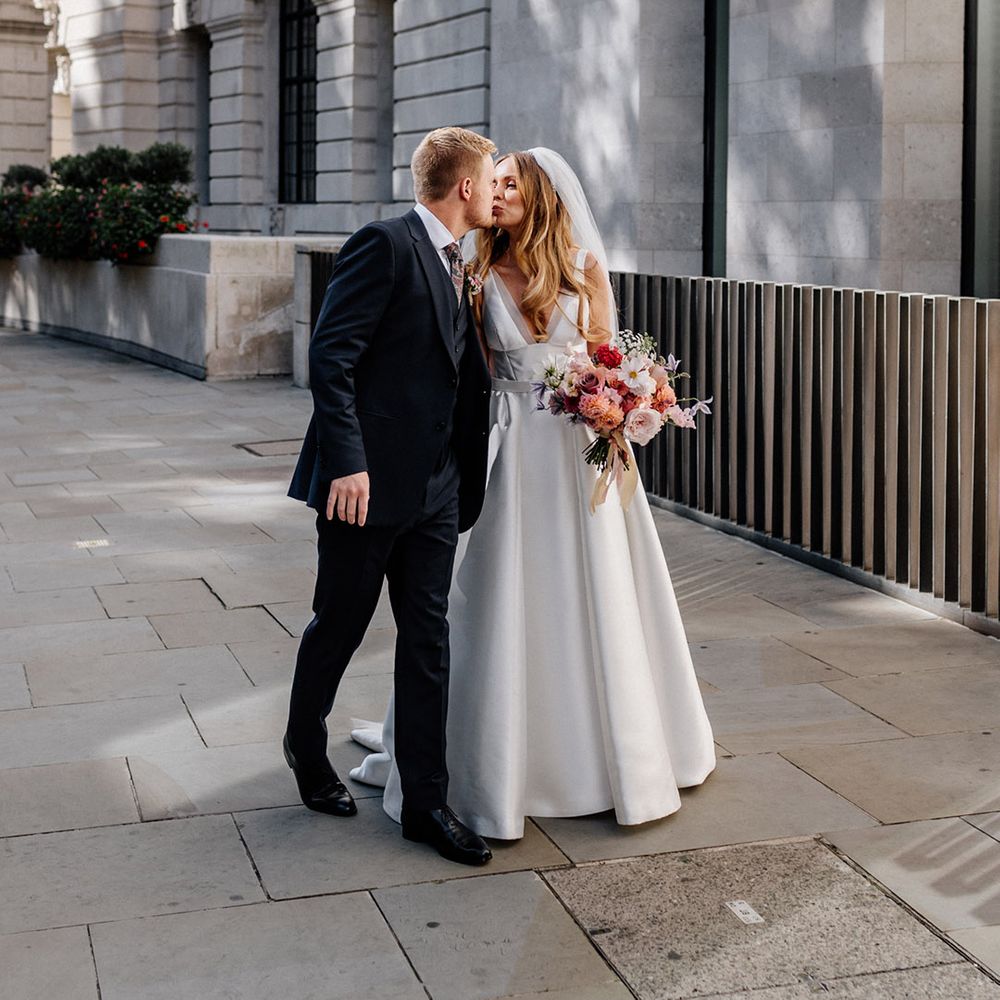Groom in a three piece navy suit kissing his bride in a Karen Willis Holmes princess wedding dress 