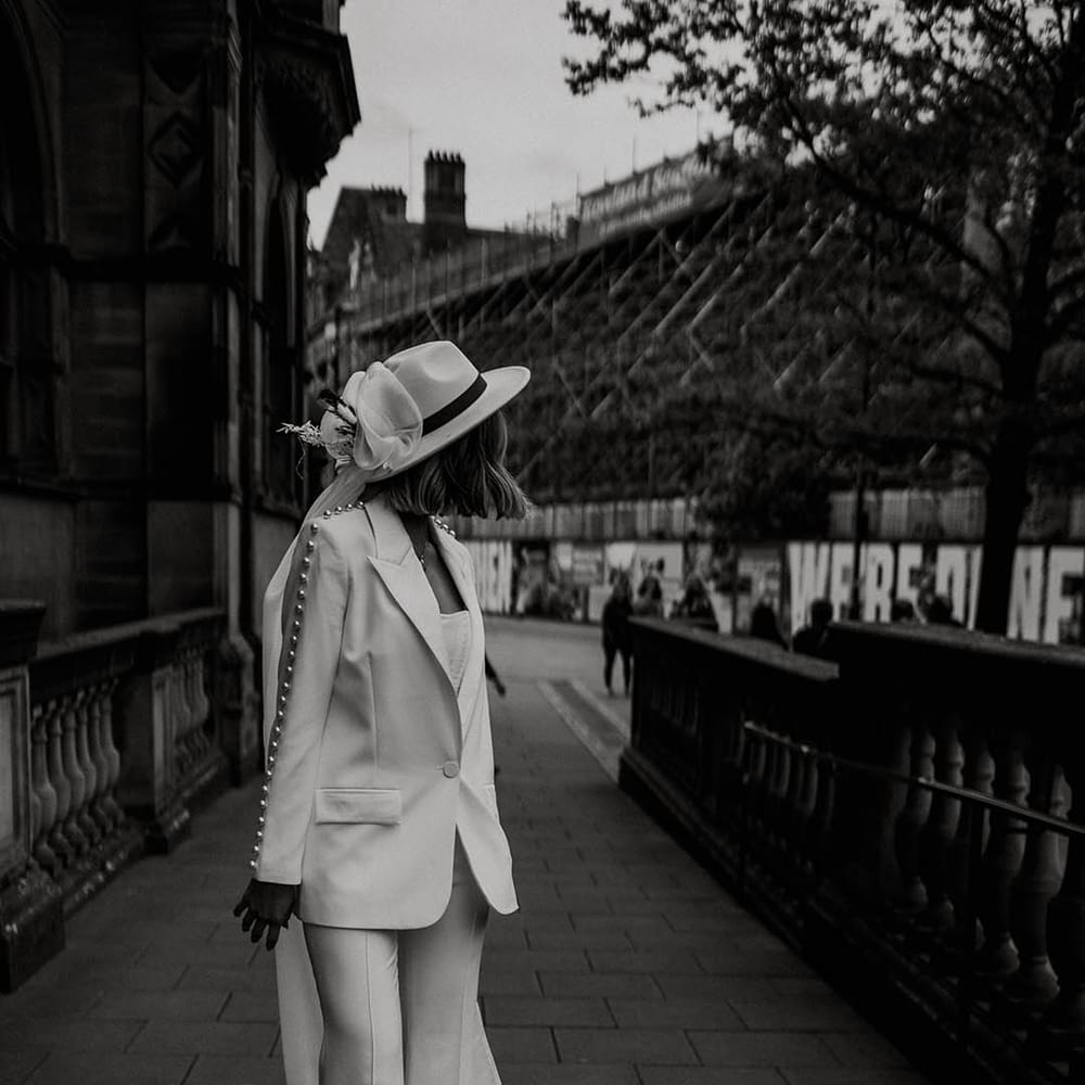 Bride in Nadine Merabi white pearl trouser wedding suit with fedora hat with veil attached for town hall wedding 