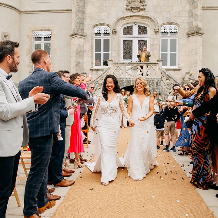 Brides walk back down the aisle as a married couple as wedding guests throw confetti 