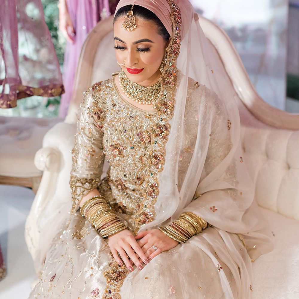 Embellished brightly coloured fabric is held above brides head on wedding day as she wears traditional saree for Walima & Nikkah