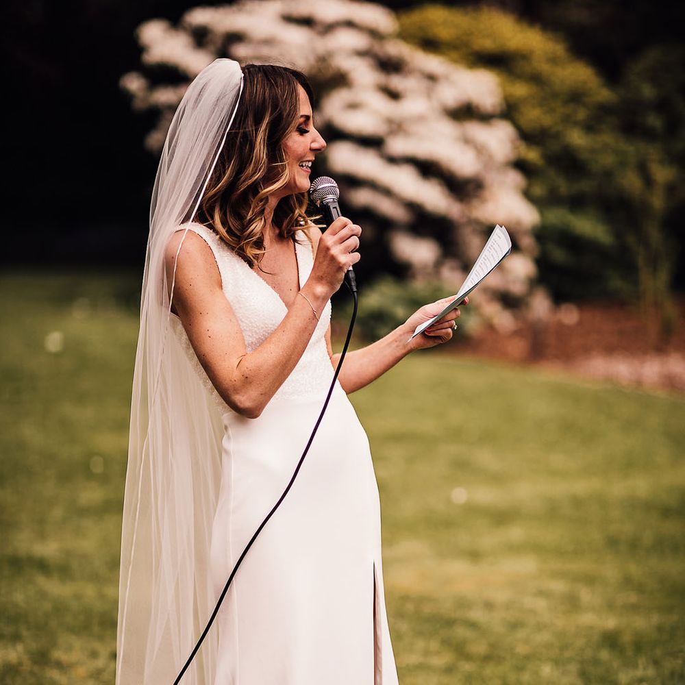 Bride stands for the outdoor reception and reads out her speech