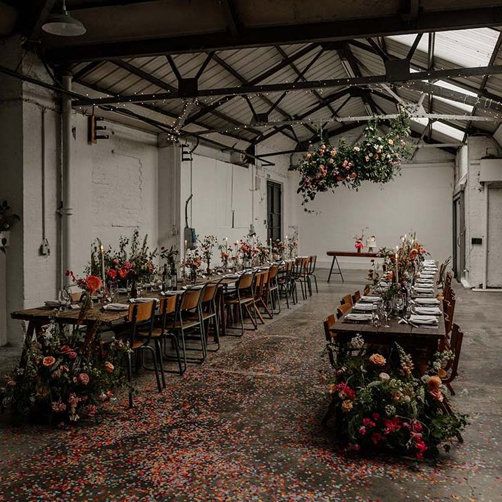 Wedding reception room at Hackney Studios with neutral, minimalistic tablescapes and pops of bright colour in the floral decorations