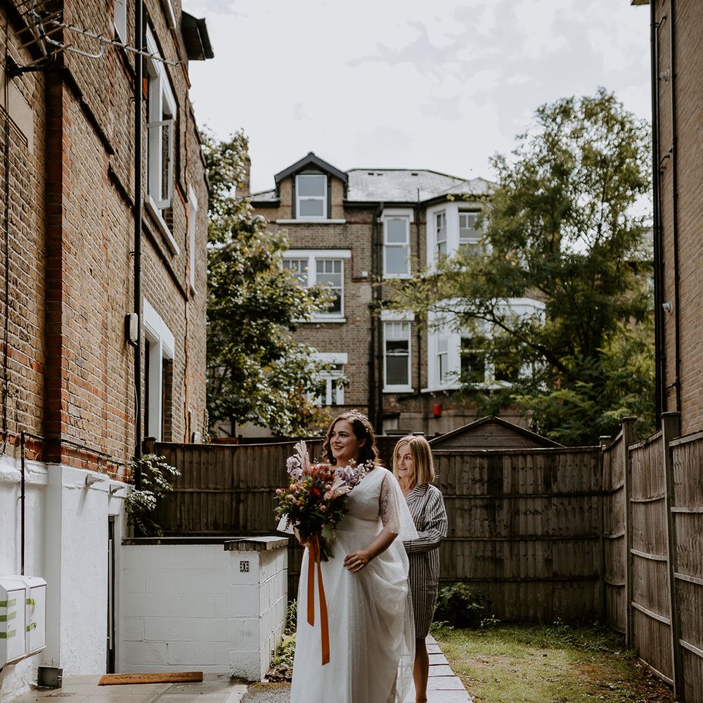 Bride walks with autumnal wedding bouquet in starry themed dress