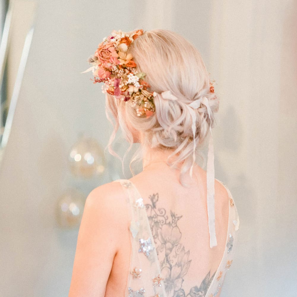 Bride wears sheer wedding dress finished with sequinned stars and flower crown in her blonde hair