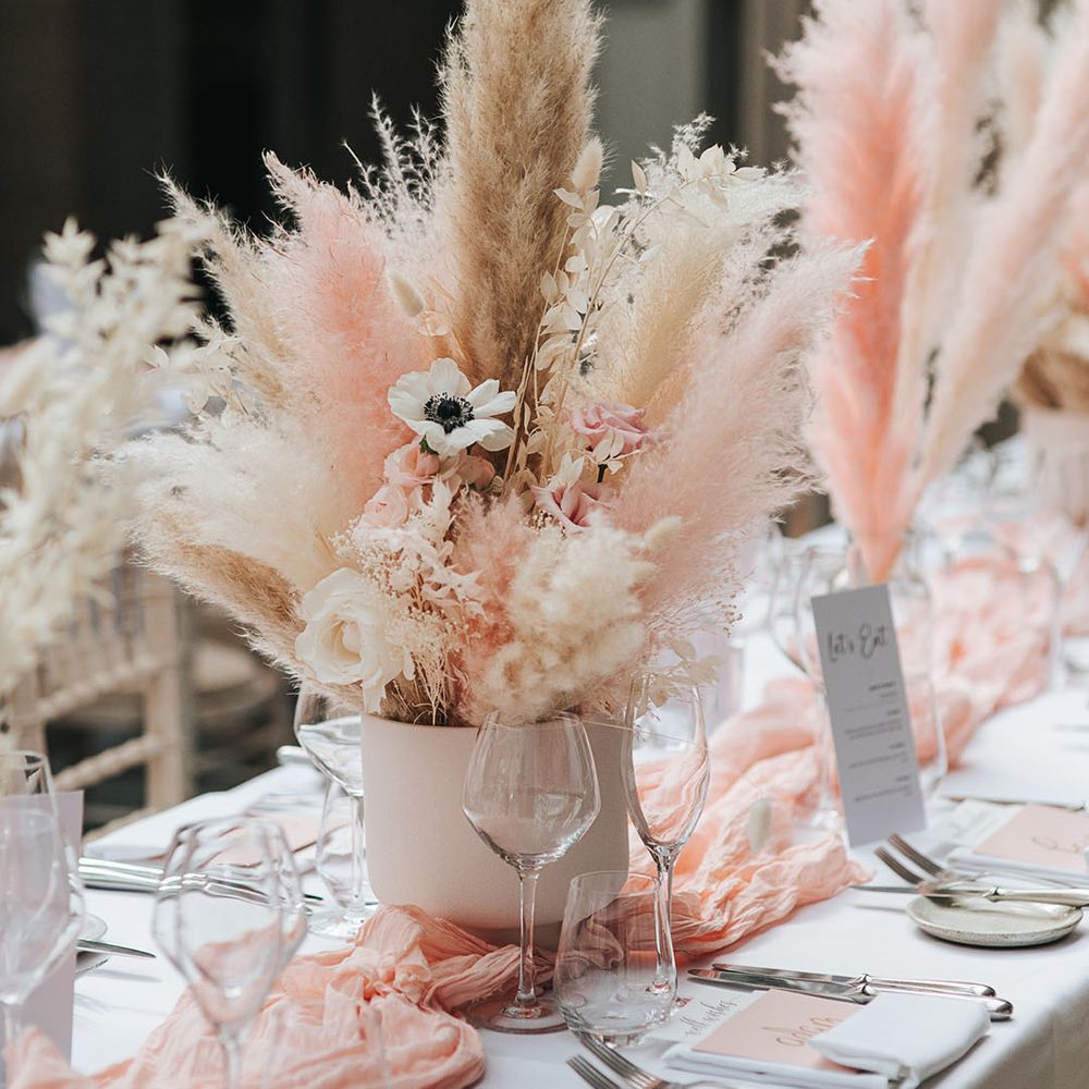 White poppy, pink and white roses and dried and dyed pampas grass centrepiece decorations on the table 