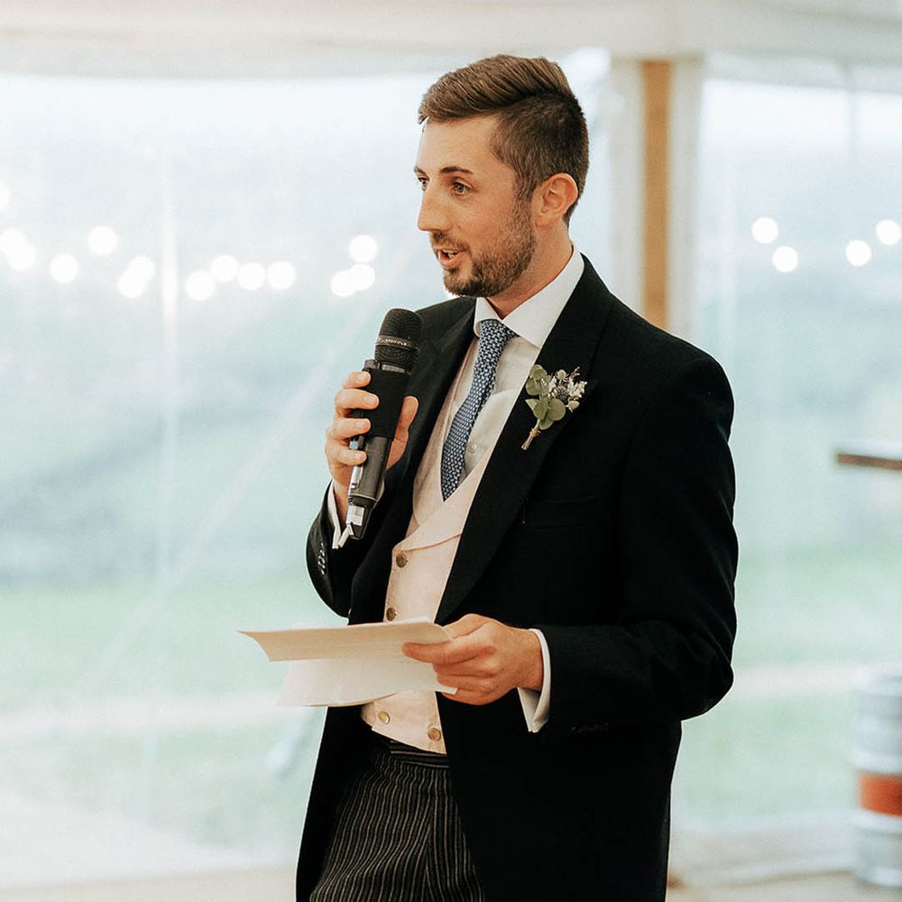 Groom wears morning suit and floral buttonhole as he gives speech during reception