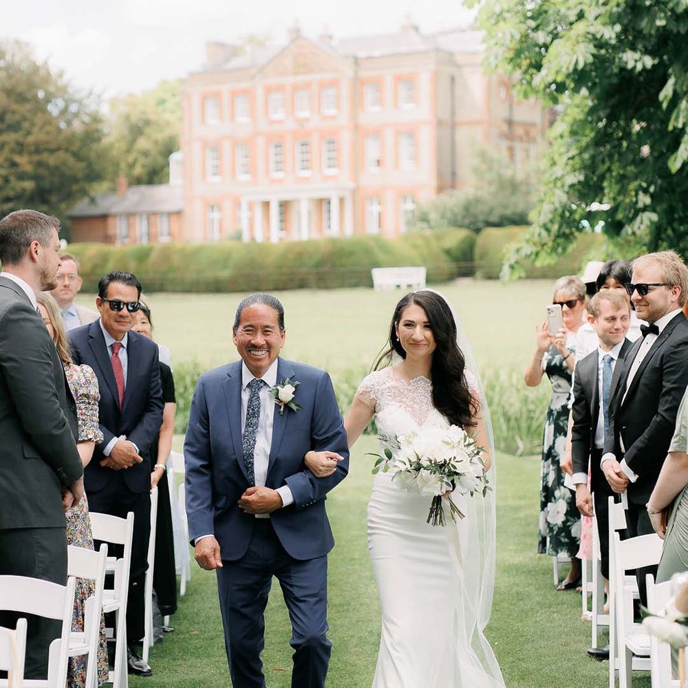 father of the bride walking his daughter down the aisle at outdoor wedding 