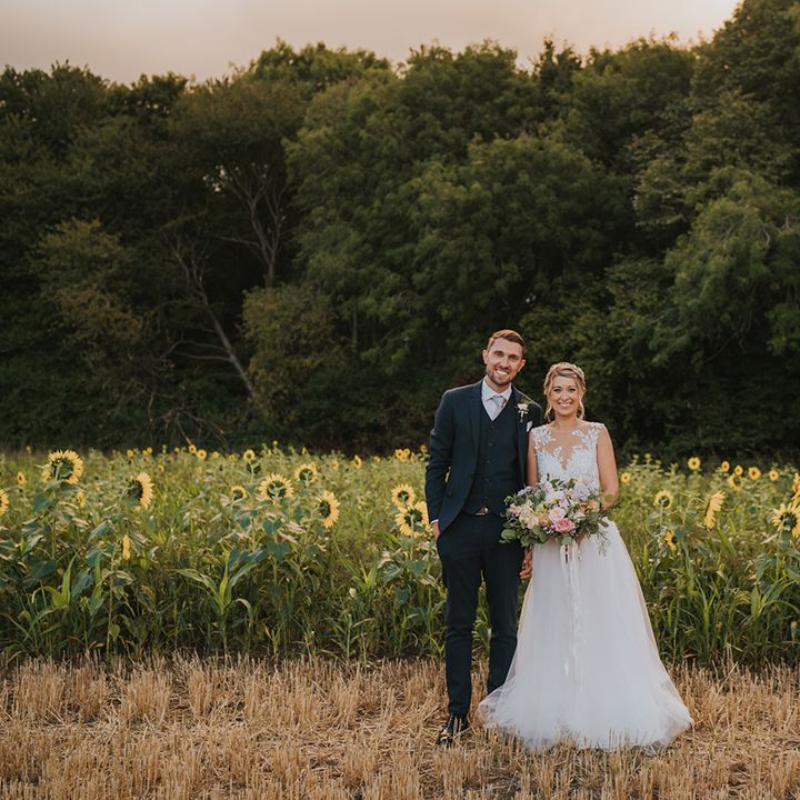The bride and groom smile together for their couple portraits in a sunflower field 