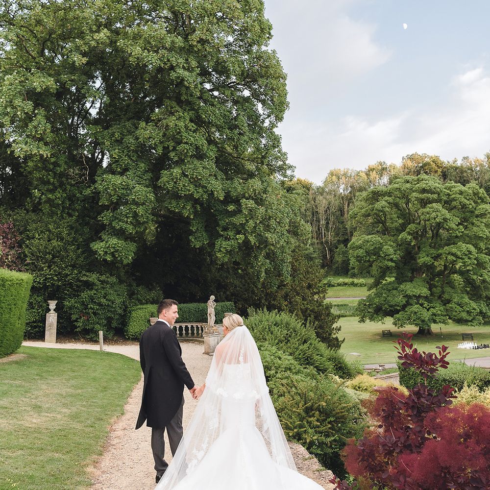 The bride and groom walk around the grounds of their classic and traditional country house wedding 