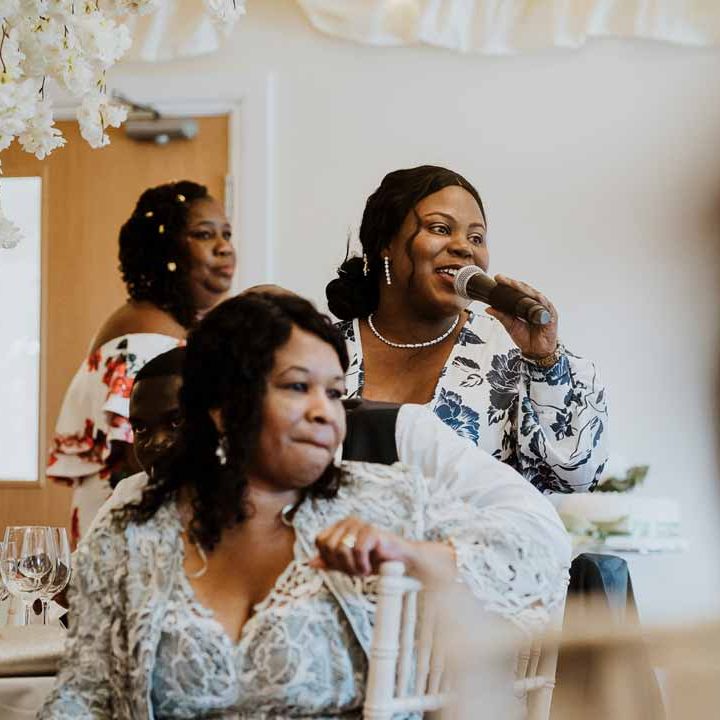 Wedding guest wearing wrap around v neck white and blue floral dress doing wedding speech at Tredudwell Manor wedding breakfast 
