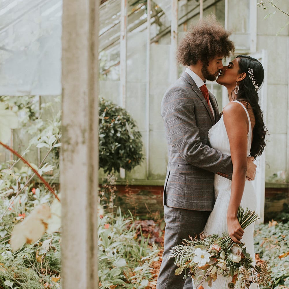 Bride and groom kissing in the glasshouse at Hooton Pagnell Hall 